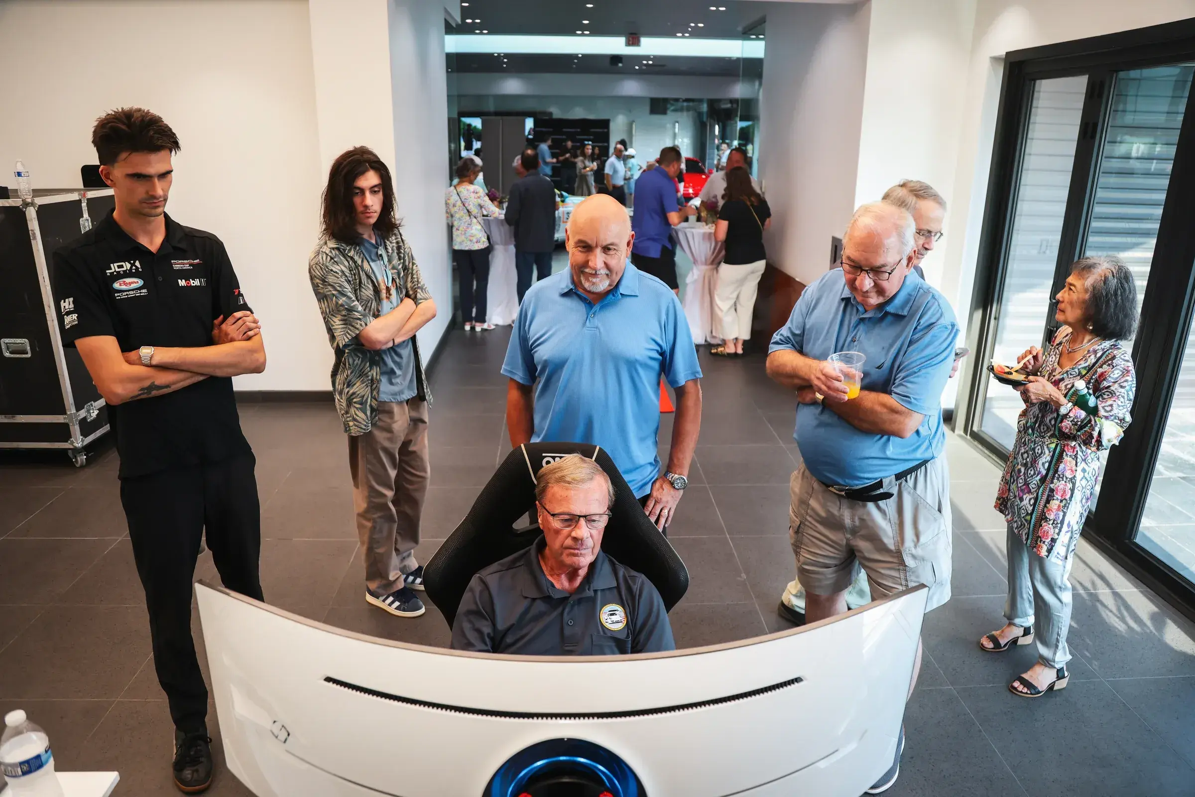 Attendees watch another attendee driving the simulator at Porsche Milwaukee North.
