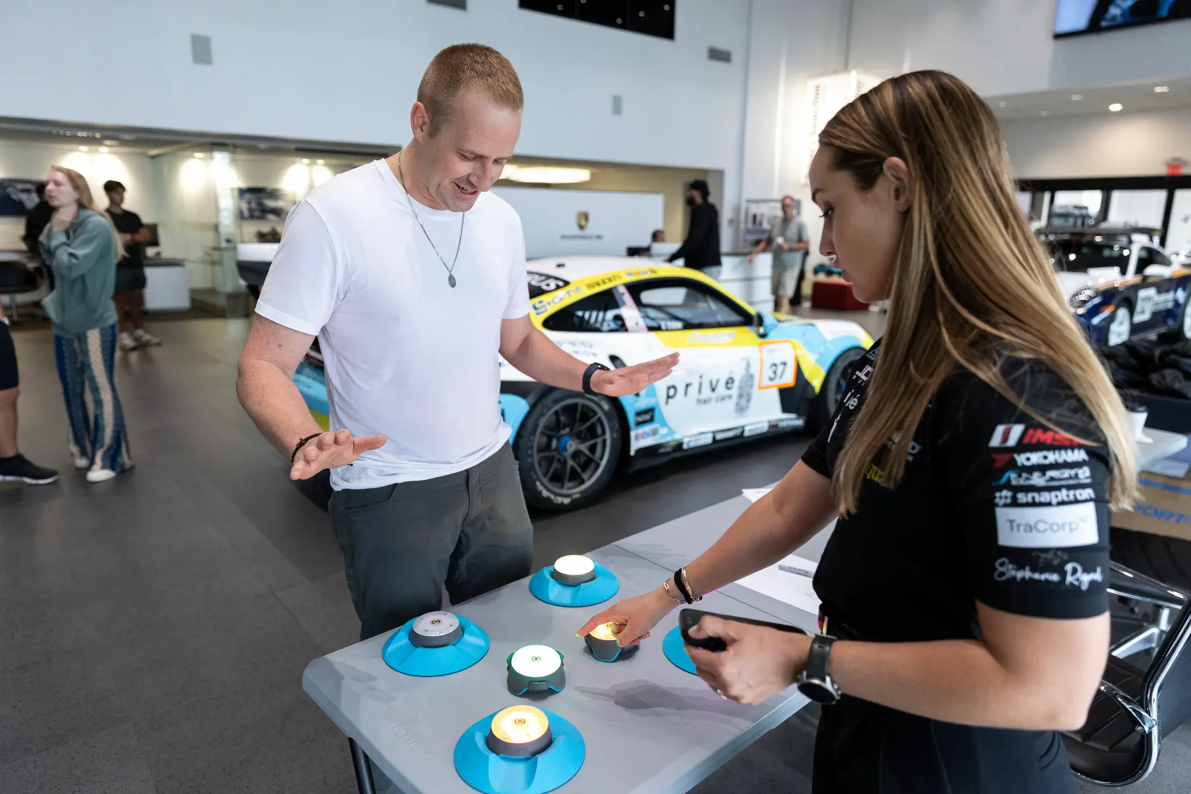 A younger attendee receives a walkthrough of simulator steering wheel commands at Tow Wood Porsche.